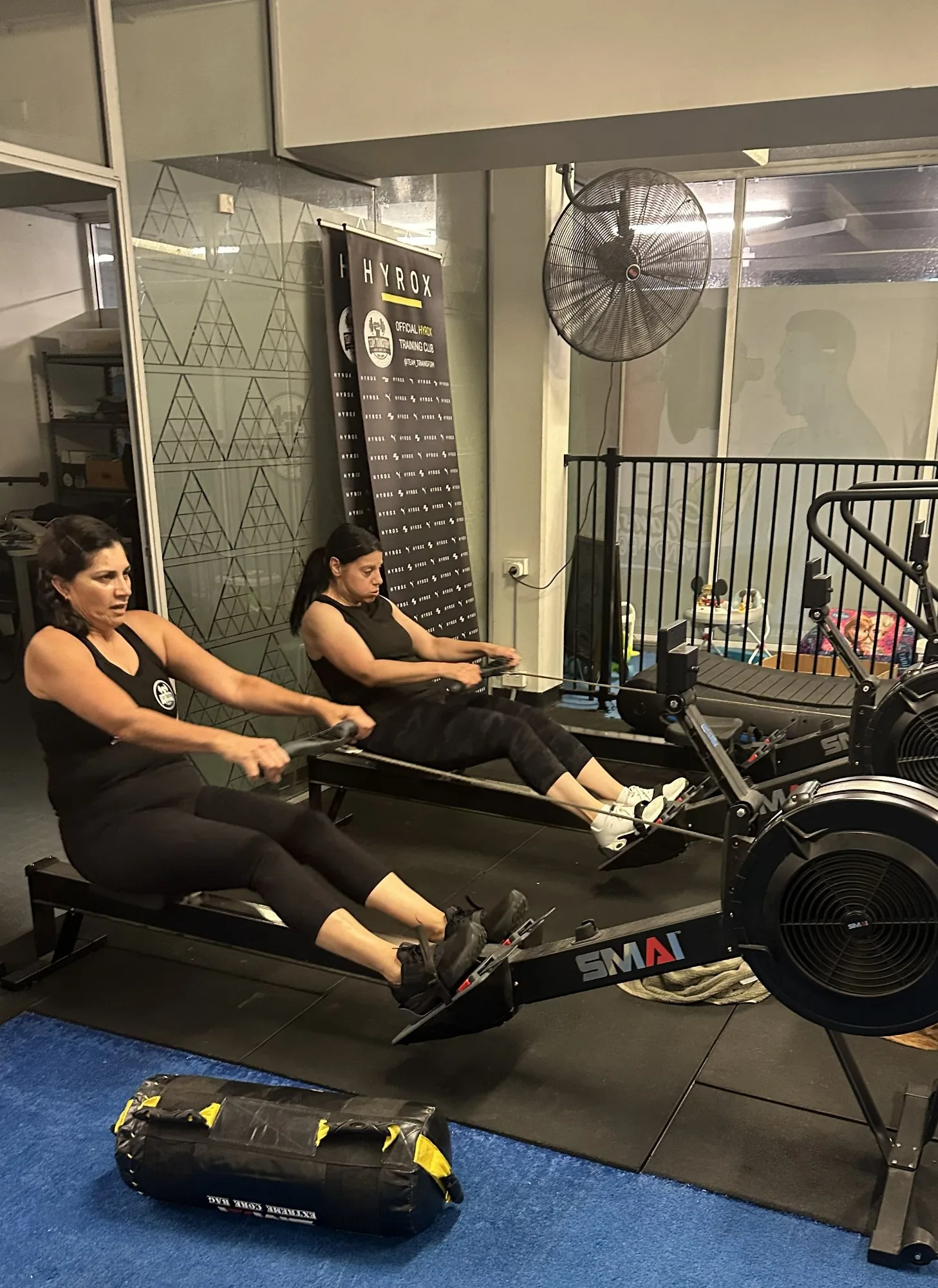 Members rowing with HYROX banner